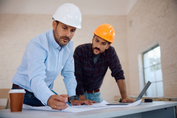 istock Housing project manager examining blueprints with construction worker during house remodeling. 2161686847