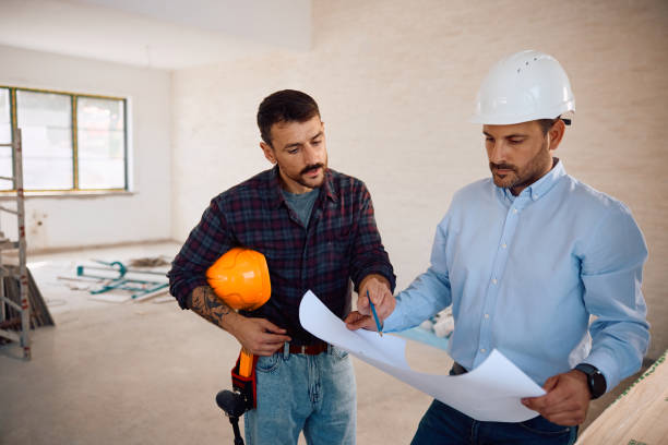 istock Architect and worker examining housing plans at construction site. 2161686863