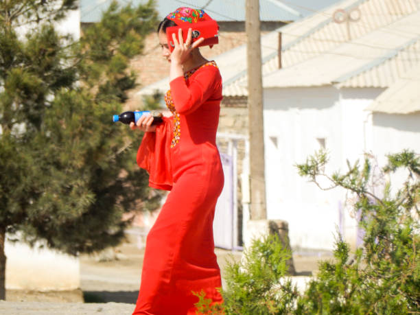 04/18/2017 - Turkmenistan - A woman in a bright red dress shields her face from the desert sun in rural Turkmenistan.