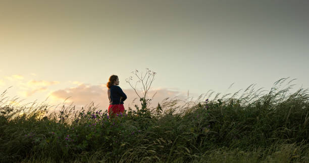 istock Tranquil Woman Looking at View in Meadow at Sunset 2161694132