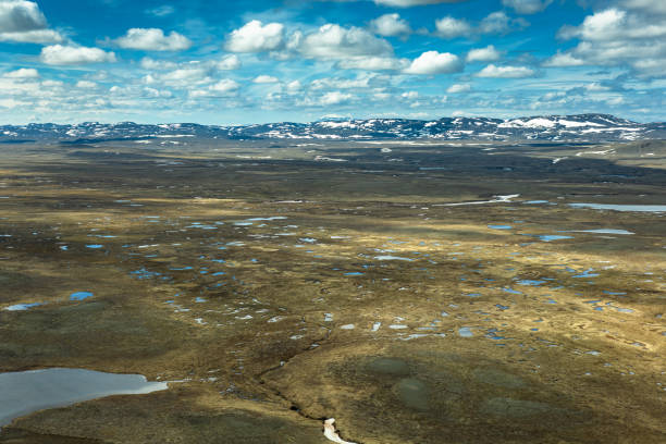 Aerial shot of the dramatic volcanic landscape of the central Highlands of Iceland on a sunny day in summer, where patches of snow are still clinging to the barren ground.