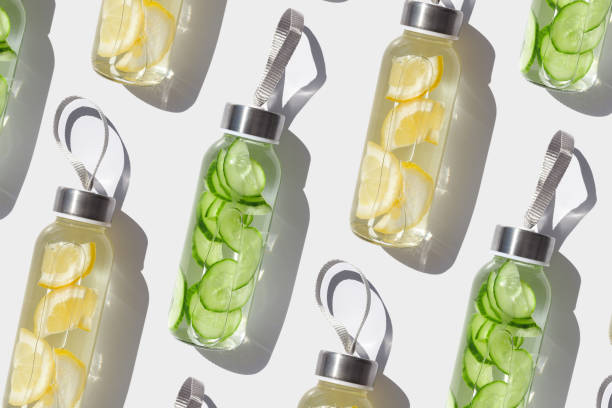 istock Glass bottles with lemon, cucumber water drink detox at sunlight on white, creative pattern. Healthy infused water boost metabolism, weight loss. Aesthetic still life, refreshing drink 2161704147