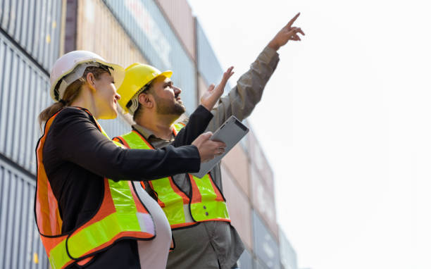 istock Pregnant Caucasian manager holding digital tablet working with male engineer technician on containers loading at cargo shipping yard. 2161706165