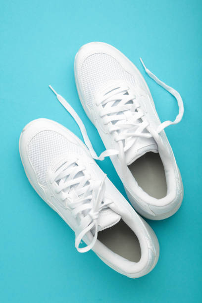 istock White sneakers on a blue background. Vertical photo 2161708700