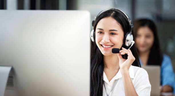 istock Portrait of smiling Asian female operator speaking with client via headset while working in call center 2161712520