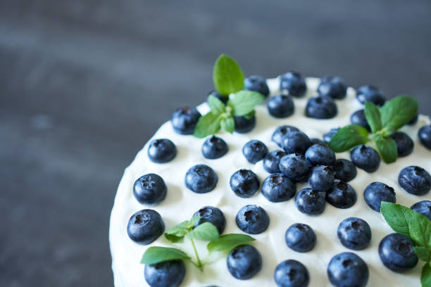Cake with fresh blueberries and mint on a dark background.