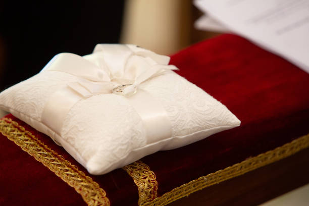 Two wedding rings are laying on a white lace pillow during a wedding ceremony
