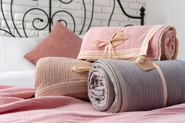 Rolled Up Soft Pink and Grey Muslin Blankets on Bed