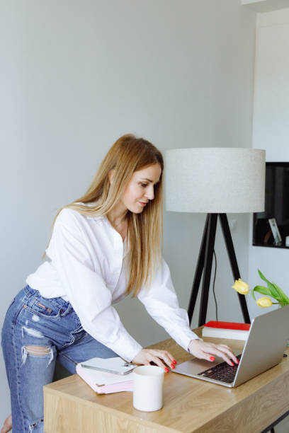 istock woman standing at the table and working at a laptop. 2161718563