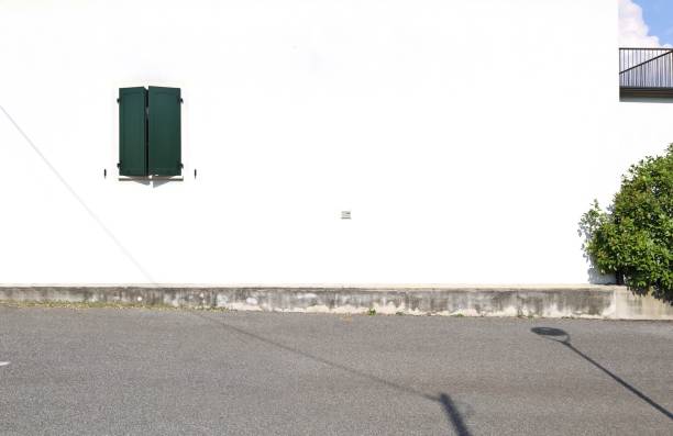 istock Closed green window shutter on a white plaster house facade at the roadside. Road in front, balcony and sky on the right 2161719058