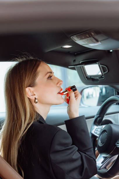istock woman paints her lips in an expensive car 2161719946