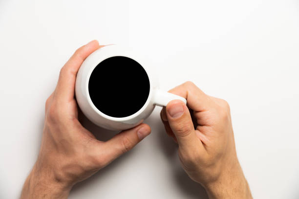 Hand holds a cup of hot chocolate cocoa drink on a white background. View from above. Flat layout