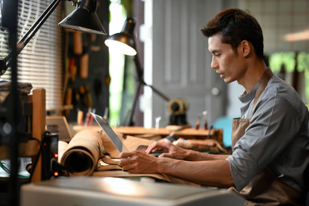 istock Handsome male entrepreneur using laptop at his leather workshop. Small business concept 2161720538