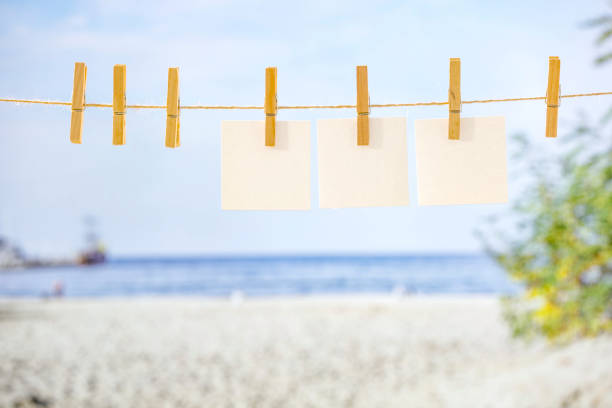 Summer beach and  wooden clothespins on a string with white blank cards for text. Copy space for products and objects display montage with  beach and seascape background.