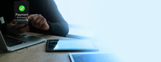 istock A person confirms a successful payment on their smartphone while working on multiple digital devices. 2161724320