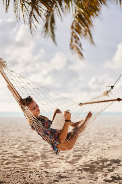 istock Relaxed woman reading a book in hammock on the beach. 2161725628