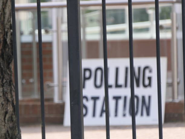 istock Polling station sign behind fence bars 2161732682