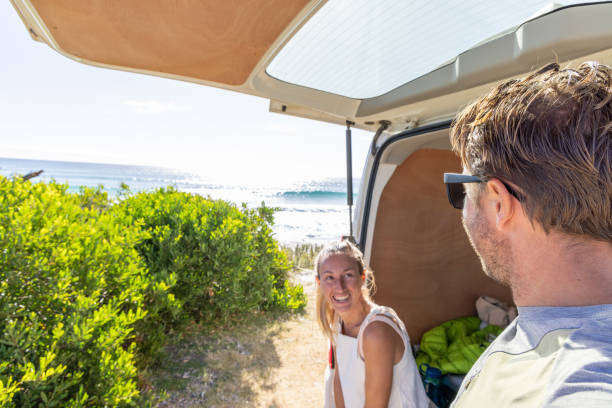 istock Happy Couple Relaxing in Open Van Trunk by the Beach 2161735732