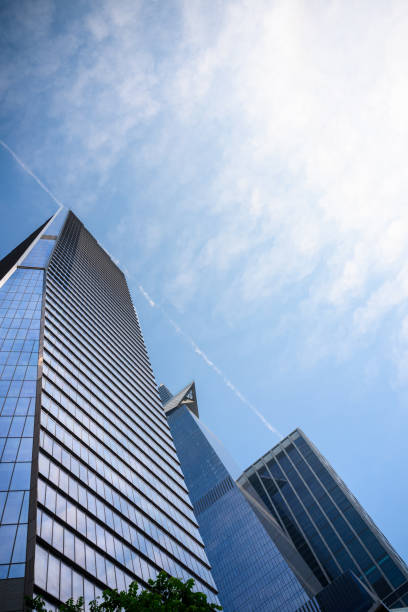 Low angle view of three modern blue glass high rises with contrail in sky