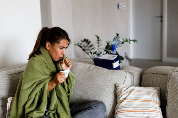 istock Young sick woman blowing nose while sitting on sofa. 2161741038