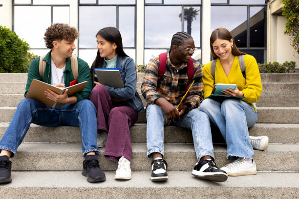 istock Happy diverse university student friends doing homework together sitting on campus steps. 2161742520
