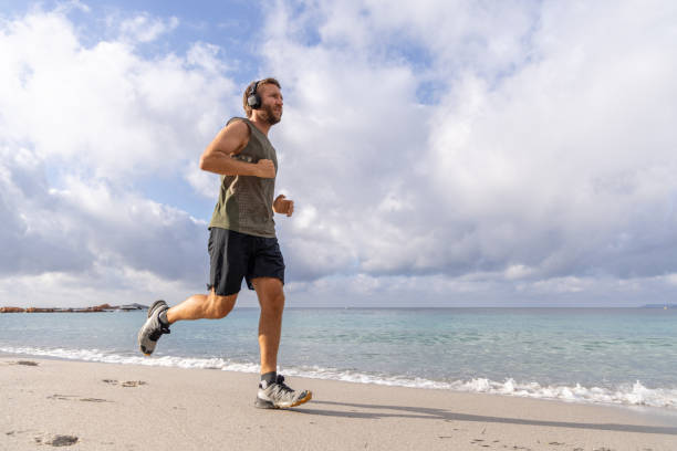 istock Man Jogging on Beach with Headphones 2161742889