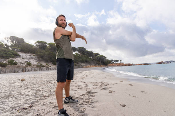 istock Man Stretching on Beach with Headphones 2161743602