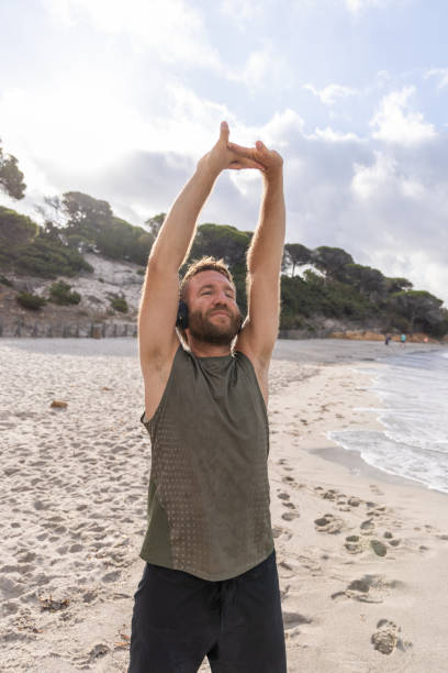 istock Man Stretching with Headphones on Beach 2161743908