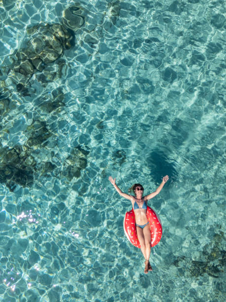 istock Woman Relaxing with Raised Arms on a Float in Clear Waters 2161744831