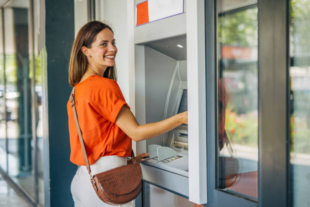 istock Beautiful young adult female smiling while using an ATM. 2161744883