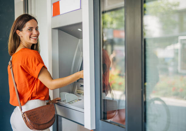 istock Beautiful young adult female smiling while using an ATM. 2161744966