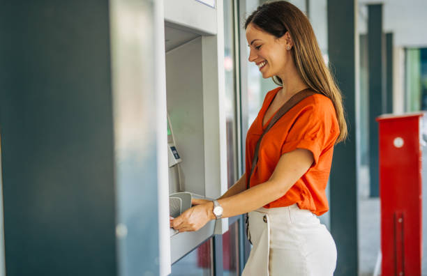 istock Beautiful young adult female smiling while using an ATM. 2161745015