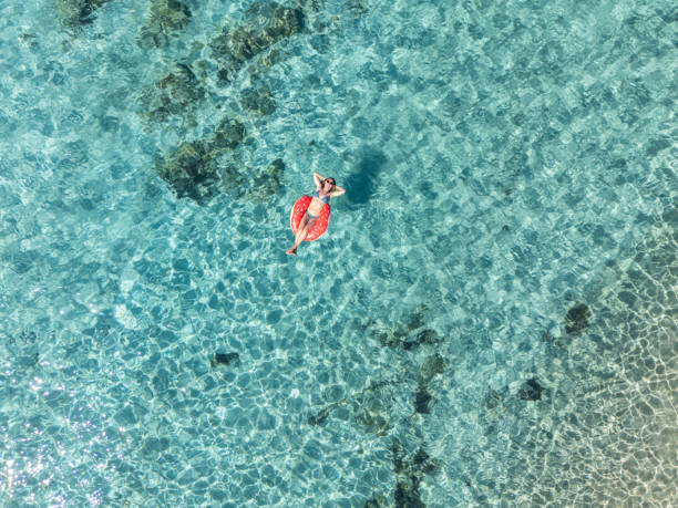 istock Woman Relaxing with Hands Behind Head on Float in Clear Waters 2161745056
