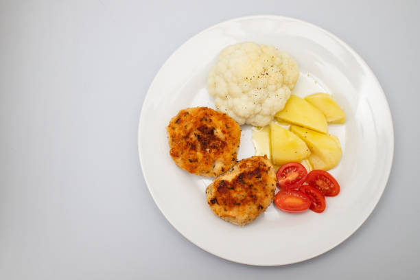 Fried chicken meatballs with boiled vegetables and salad on white plate