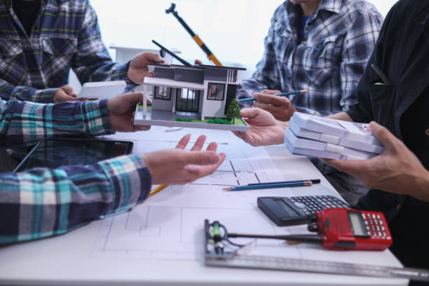 istock team of engineers and architects discuss house plan design and estimate construction prices to suit the construction budget. Checking blueprints and documents with a team of engineers and architects 2161753620