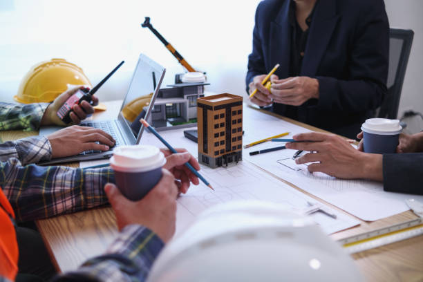 istock team of engineers and architects discuss house plan design and estimate construction prices to suit the construction budget. Checking blueprints and documents with a team of engineers and architects 2161753795