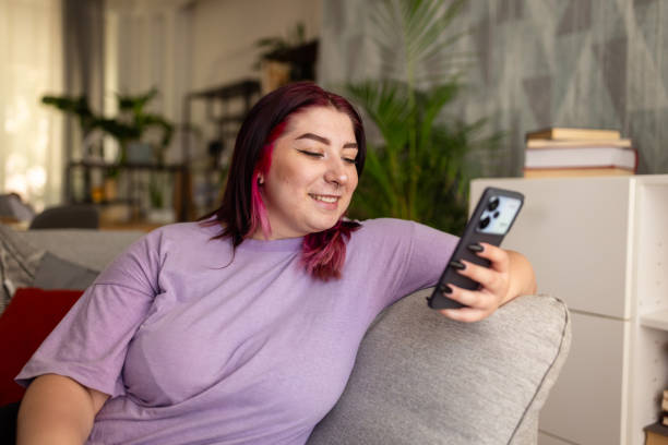 istock Smiling woman relaxing on a sofa, looking at her phone 2161753908