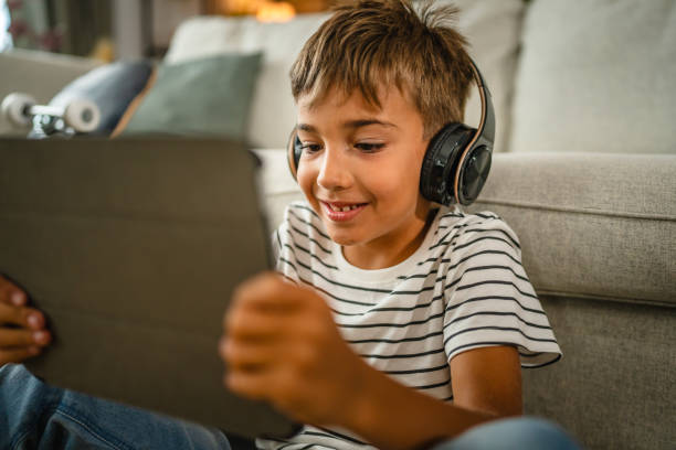 istock young boy with headphones sit on the floor and use digital tablet 2161755872