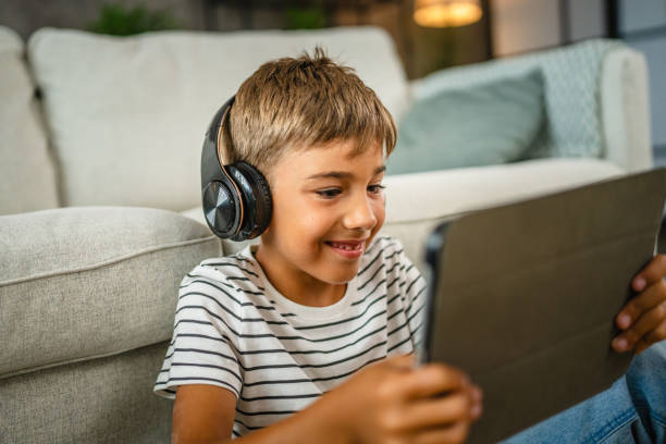 istock young boy with headphones sit on the floor and use digital tablet 2161755955