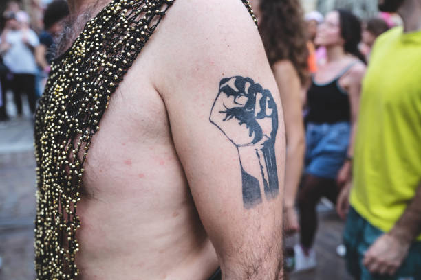 Raised fist tattoo on the arm of a man marching at LGBTQIA+ pride in Turin, Italy, 15 June 2024.