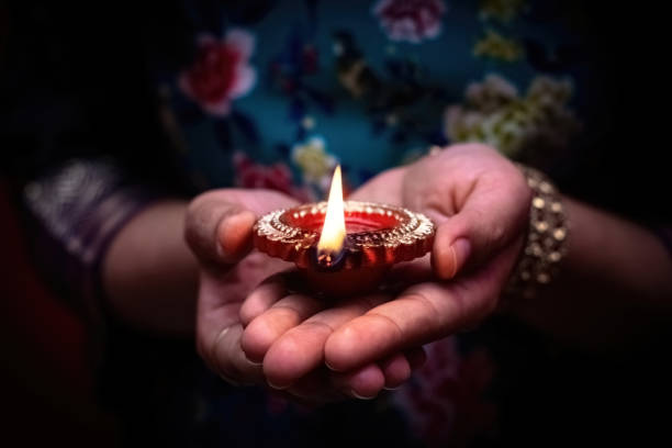 istock Happy Diwali. Woman's hands holding lit (Diya). Diwali celebrations 2161759372