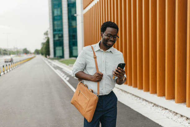istock Man smiling at his phone while walking down the street. 2161765417
