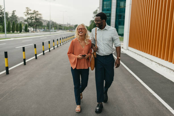 istock Man and woman smiling while walking down the street. 2161765519