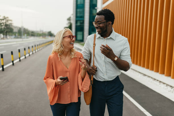 istock Colleagues conversing while walking with phones in hands 2161765534