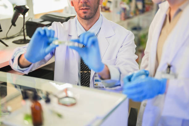 scientists perform experiments and record data. people arranges equipment with test tubes and chemicals for producing medicine and biochemistry. man hold tubes of chemical liquids and plant samples.