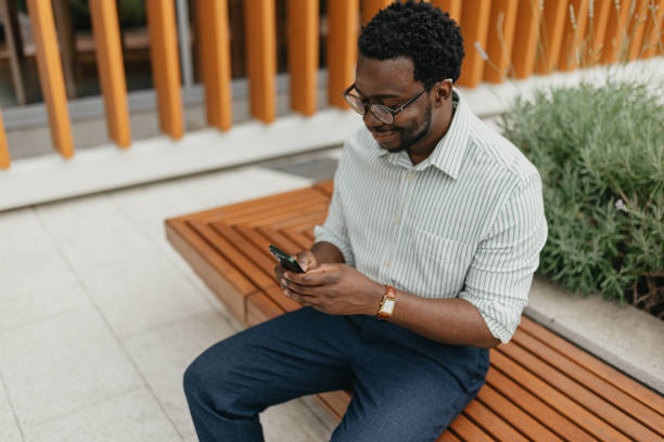 istock Man texting on smart phone sitting outdoors on bench 2161766639