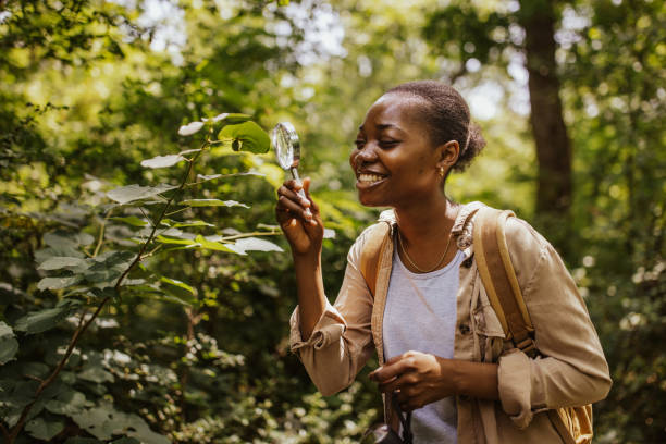 istock Happy woman studies leaf in forest with magnifying glass. 2161766649