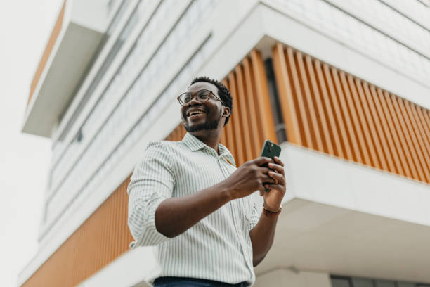 istock Man standing outdoors holding phone near modern building. 2161767134