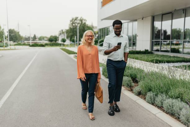 istock Two colleagues walking together, checking phone. 2161767218