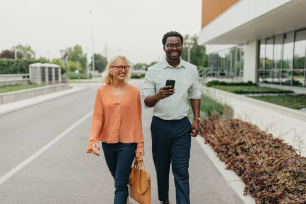 istock Two people walking outdoors discussing business plans. 2161767282